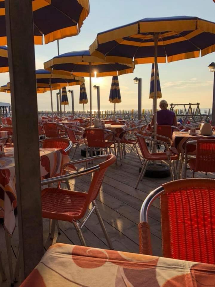 un restaurant en plein air avec tables, chaises et parasols dans l'établissement Hotel Esperia, à Caorle