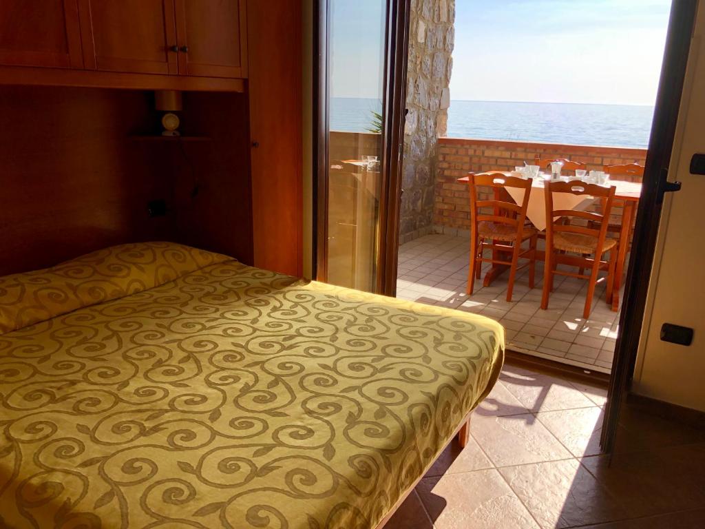 une chambre avec un lit et un balcon avec une table dans l'établissement Residence Le Palme - Appartamenti sul mare - Spiaggia tra Palinuro e Caprioli, à Pisciotta