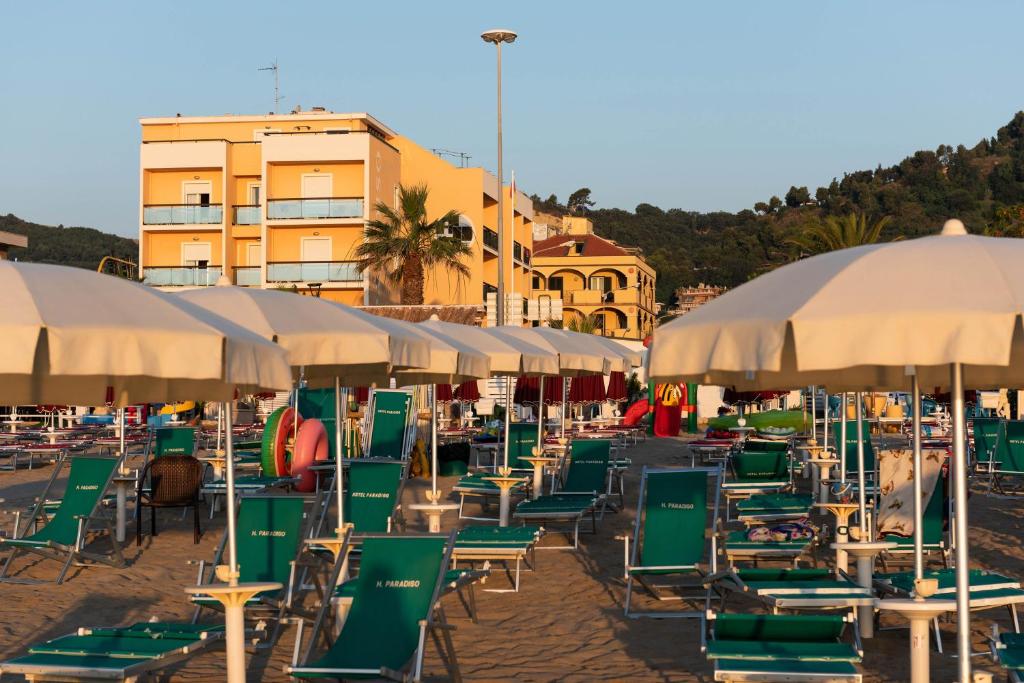 un groupe de chaises et de parasols sur une plage dans l'établissement Hotel Paradiso, à Grottammare