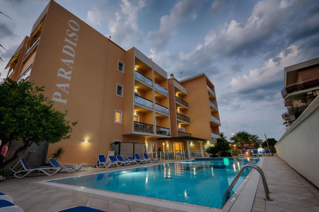 un hôtel avec une piscine devant un bâtiment dans l'établissement Hotel Paradiso, à Grottammare