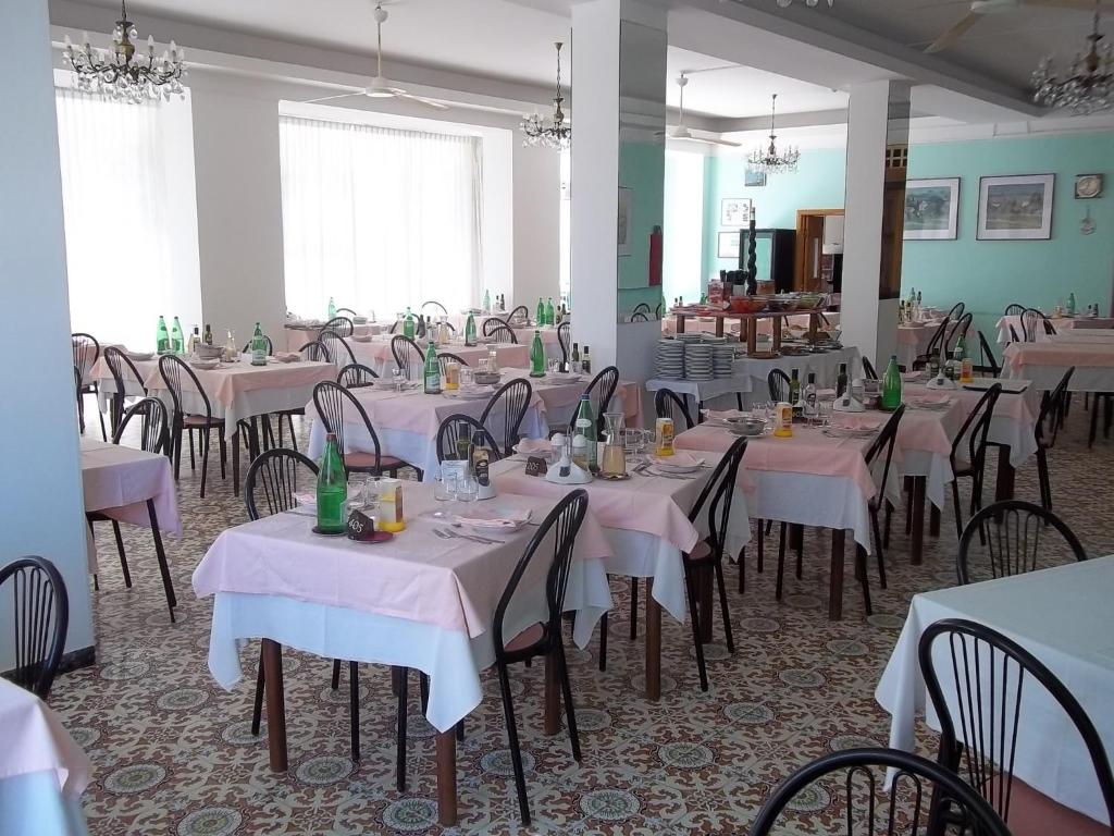 une salle à manger avec des tables et des chaises recouvertes de nappes blanches dans l'établissement Hotel Italia, à Senigallia