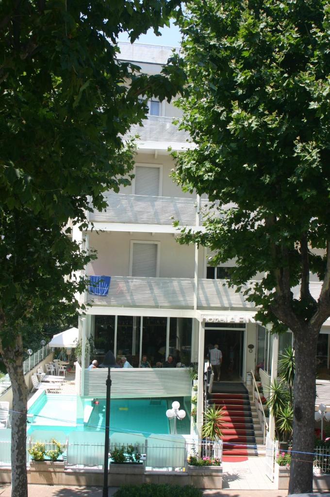 un bâtiment avec une piscine devant dans l'établissement Hotel Arno, à Rimini