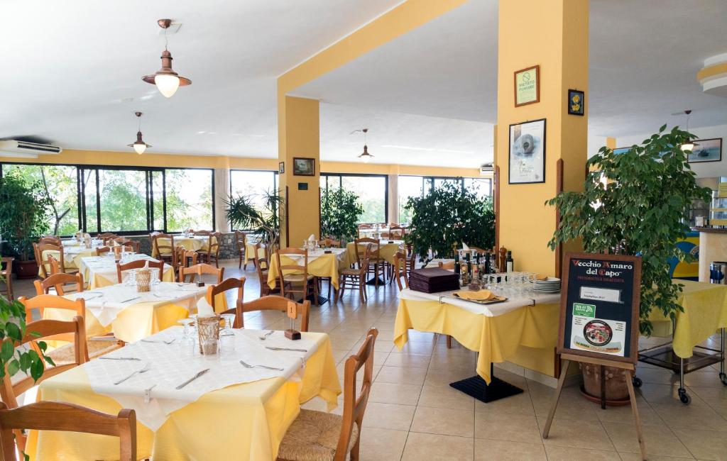 un restaurant avec des tables et des chaises jaunes et des fenêtres dans l'établissement Happy Days, à Capo Vaticano