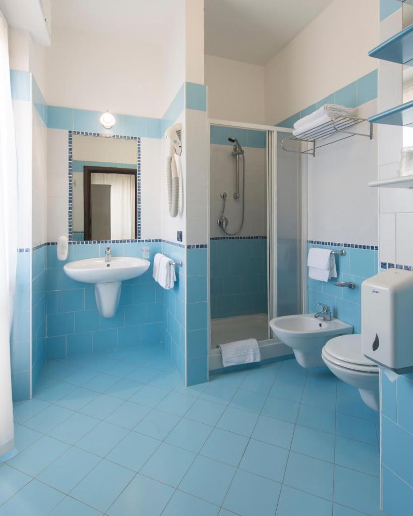 une salle de bain bleue avec deux lavabos et des toilettes dans l'établissement Grand Hotel Adriatico, à Montesilvano