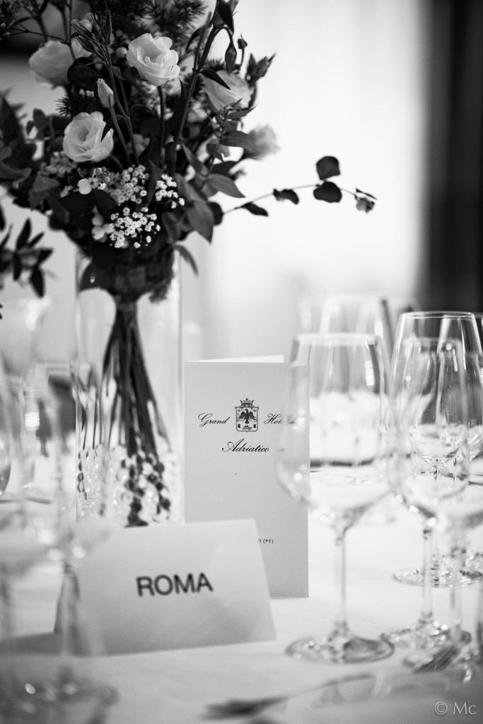 une table avec des verres à vin et un vase avec des fleurs dans l'établissement Grand Hotel Adriatico, à Montesilvano