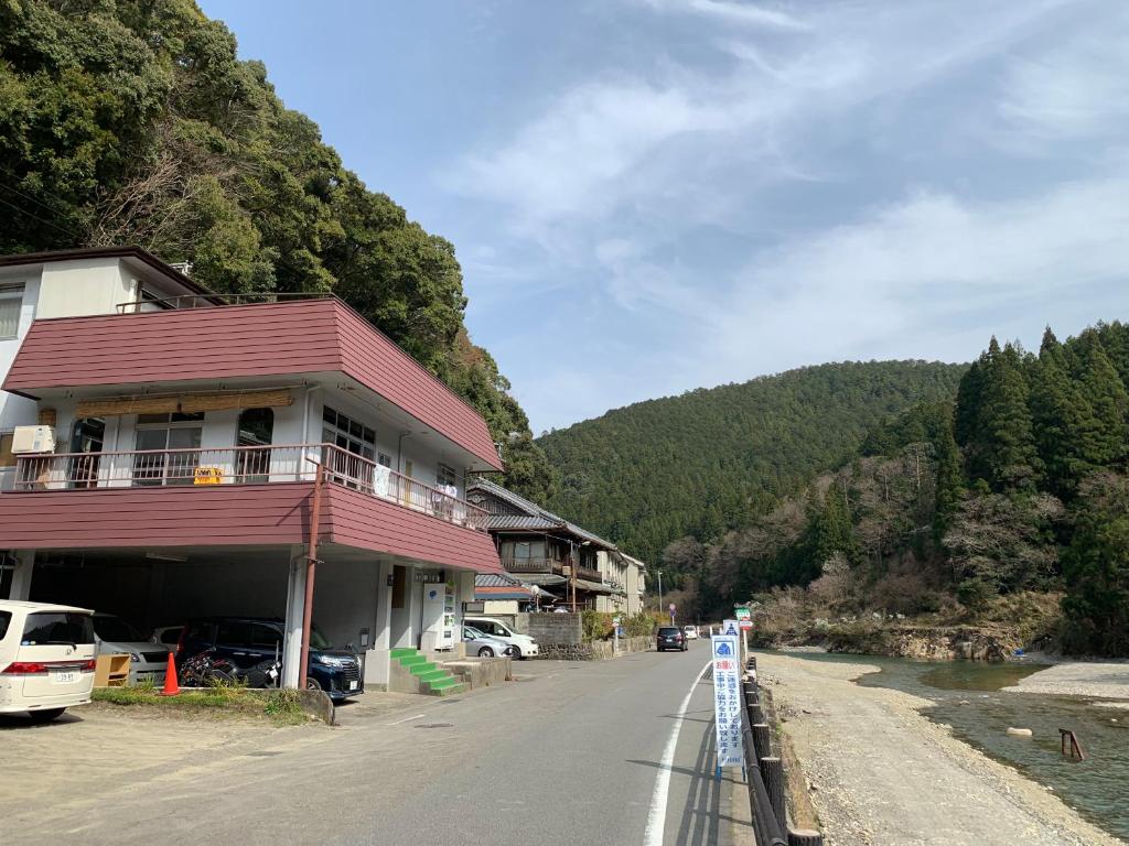 un bâtiment situé sur le côté d'une route à côté d'une montagne dans l'établissement Minshuku Sumiya, à Tanabe