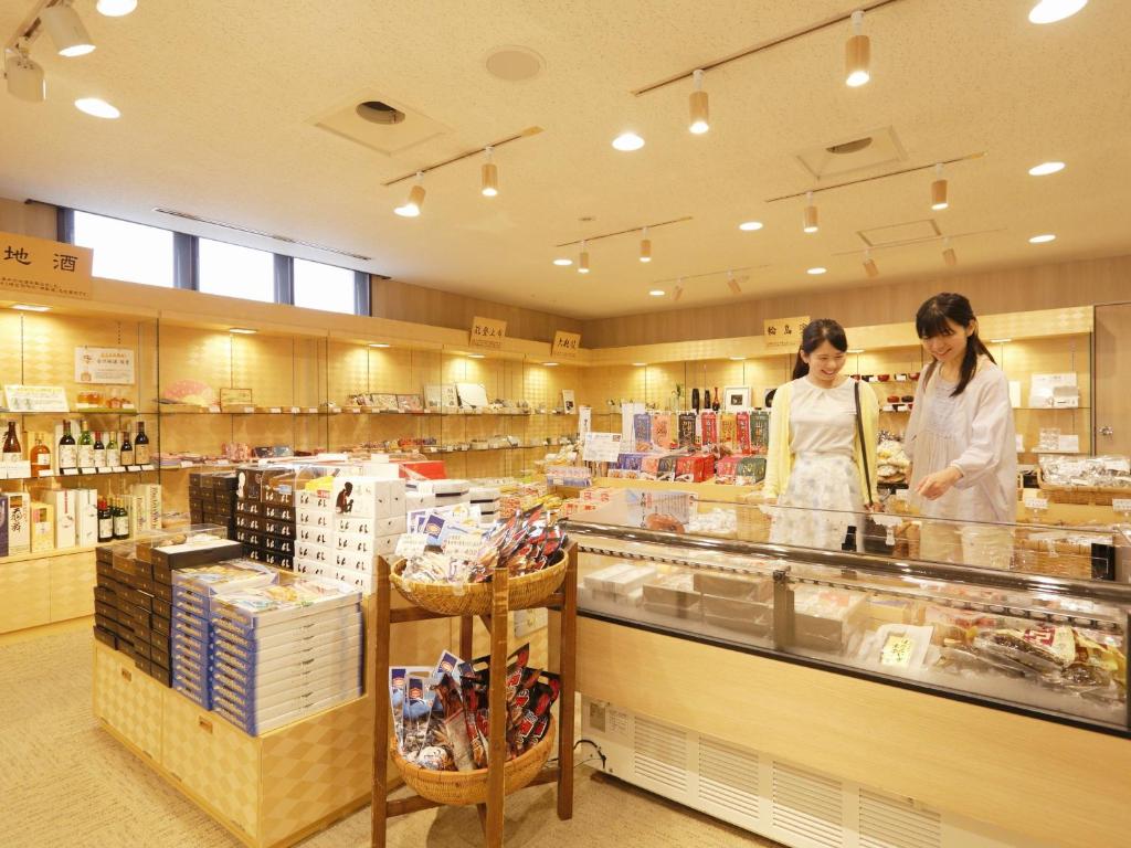 deux femmes debout derrière un comptoir dans un magasin dans l'établissement Kyukamura Noto-Chirihama, à Hakui
