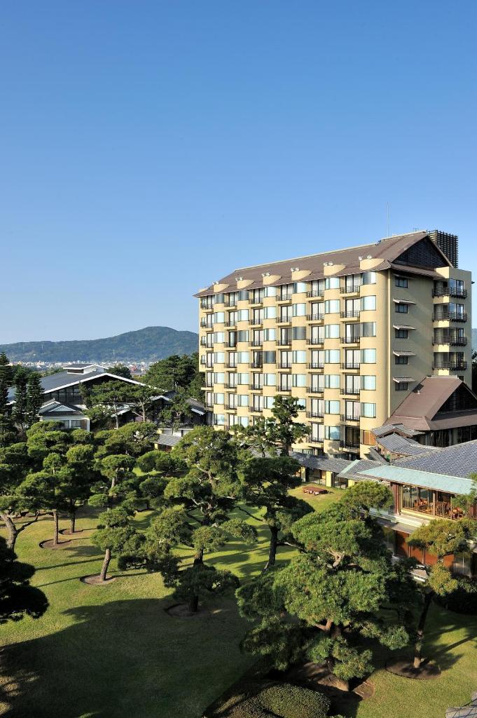 un grand immeuble d'appartements avec des arbres devant lui dans l'établissement Kagoshima Sunamushionsen Ibusuki Hakusuikan, à Ibusuki