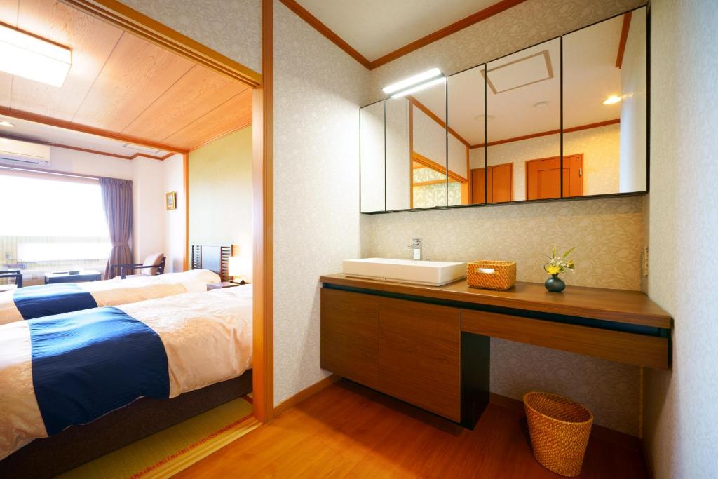 une chambre avec un lit, un lavabo et un miroir dans l'établissement Tenku Yubo Seikaiso, à Beppu