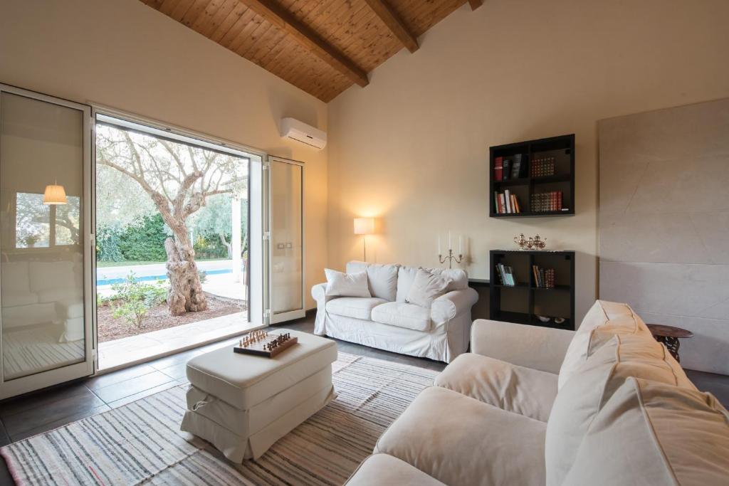 un salon avec des meubles blancs et une grande fenêtre dans l'établissement Villa Silva - IsulaTravel, à Modica