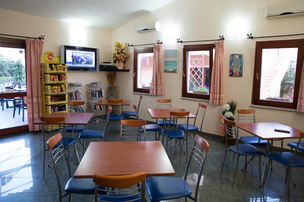 un restaurant avec des tables et des chaises dans une salle dans l'établissement Residence Corte Dei Venti, à Budoni