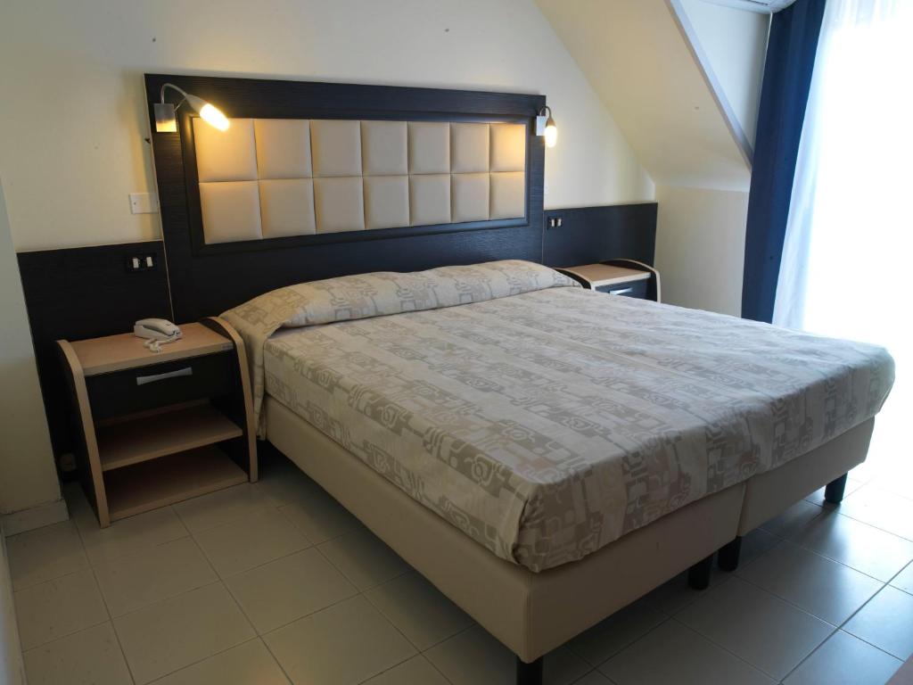 une chambre avec un grand lit et deux tables de nuit dans l'établissement Hotel Arno, à Rimini
