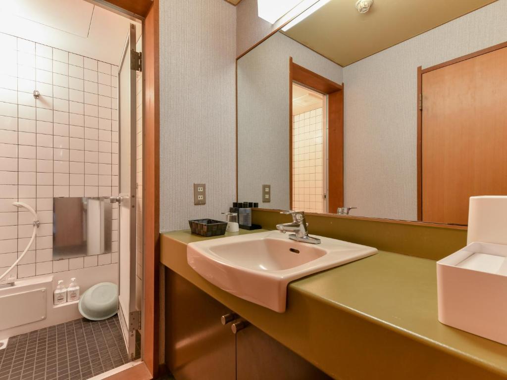 une salle de bain avec un lavabo et un miroir dans l'établissement Awara Onsen Minoya Taiheikaku, à Awara
