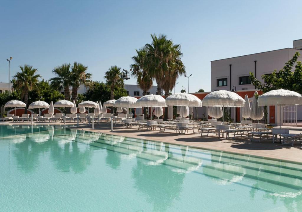 - une piscine avec des parasols, des chaises et des tables dans l'établissement Chiusurelle Village Resort, à Punta Prosciutto