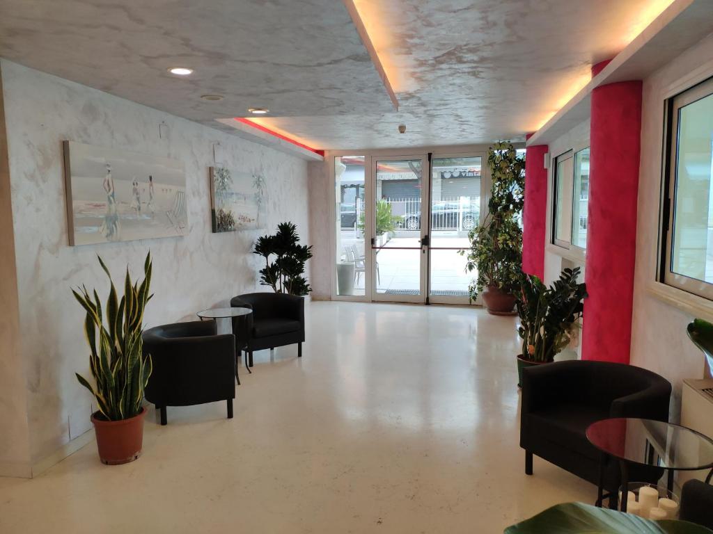 une salle d'attente avec des chaises, des tables et des plantes dans l'établissement Hotel Caesar, à Rimini