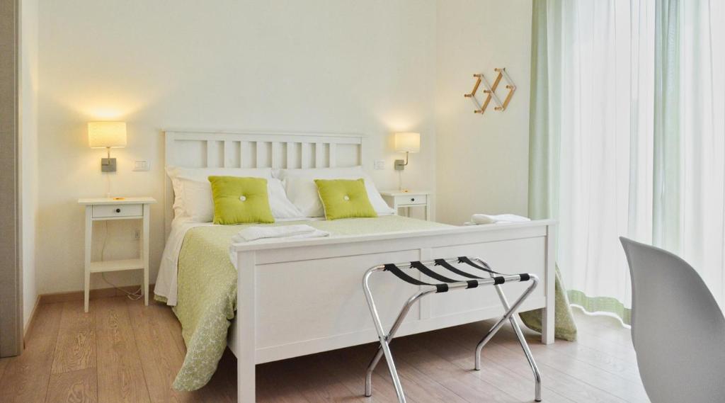 une chambre blanche avec un lit blanc avec des oreillers verts dans l'établissement Petit Hotel, à Lido di Camaiore