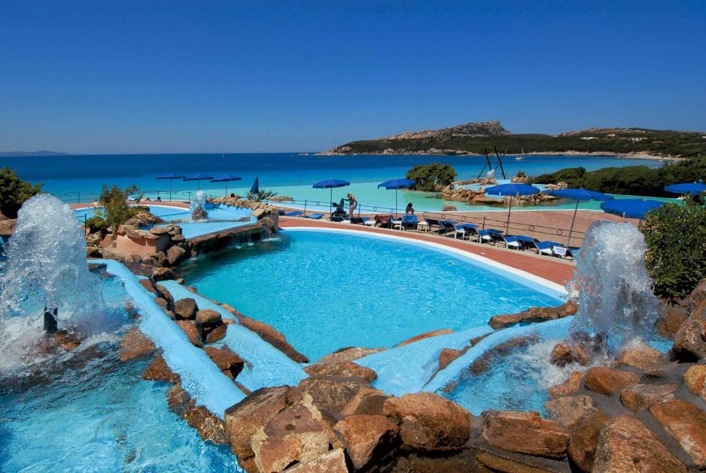 - une piscine avec des fontaines d'eau dans un complexe dans l'établissement COLONNA GRAND HOTEL CAPO TESTA, a Colonna Luxury Beach Hotel, Santa Teresa Sardegna, à Santa Teresa Gallura