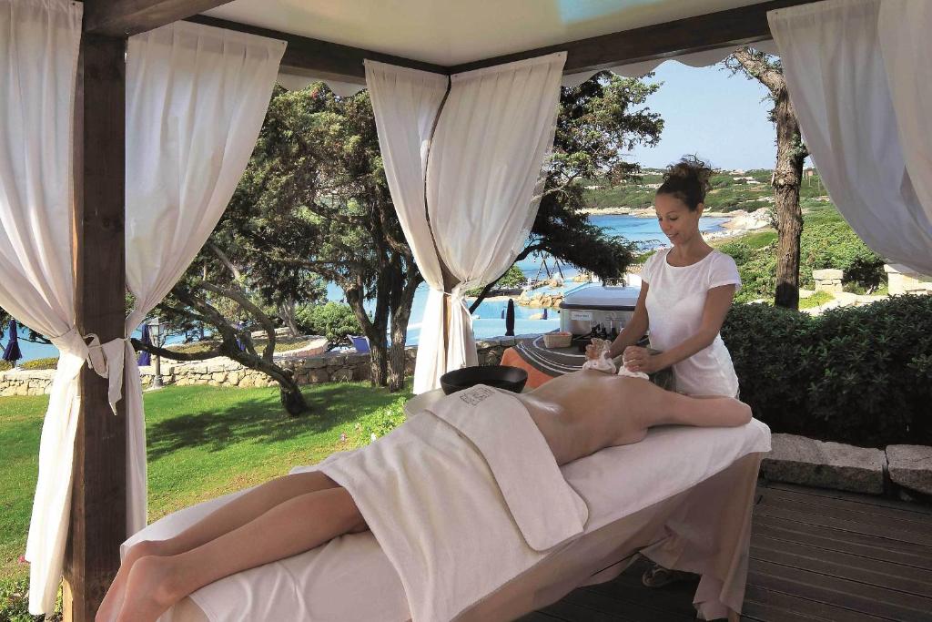 une femme donnant un massage à un homme sur un lit dans l'établissement COLONNA GRAND HOTEL CAPO TESTA, a Colonna Luxury Beach Hotel, Santa Teresa Sardegna, à Santa Teresa Gallura