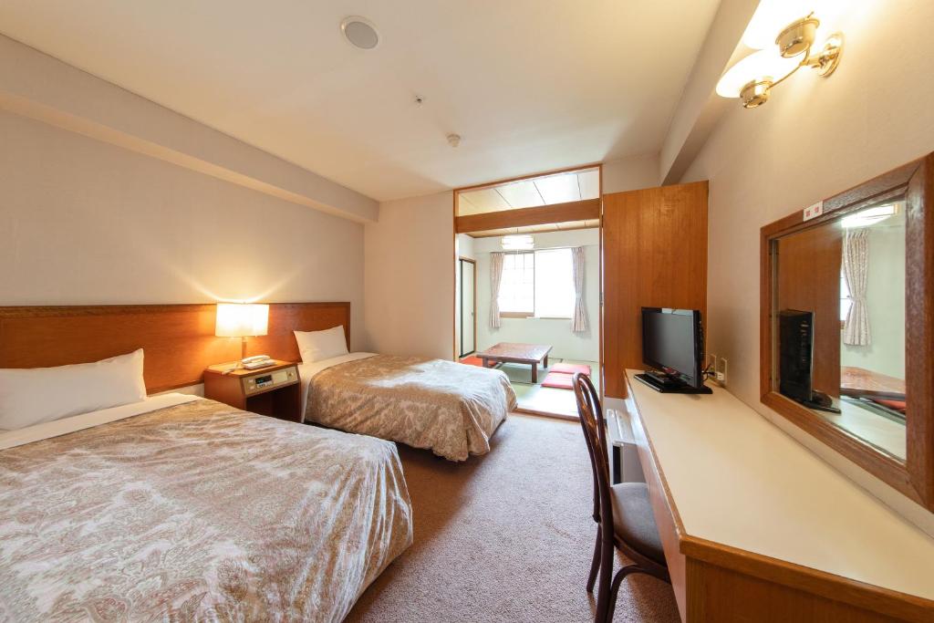 une chambre d'hôtel avec deux lits et une télévision dans l'établissement Akakura Hotel, à Myōkō