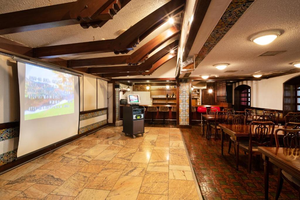 un restaurant avec un écran de projection, des tables et des chaises dans l'établissement Akakura Hotel, à Myōkō