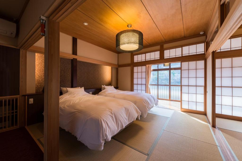 une chambre avec deux lits dans une pièce avec fenêtres dans l'établissement Takanosukan, à Sekikawa