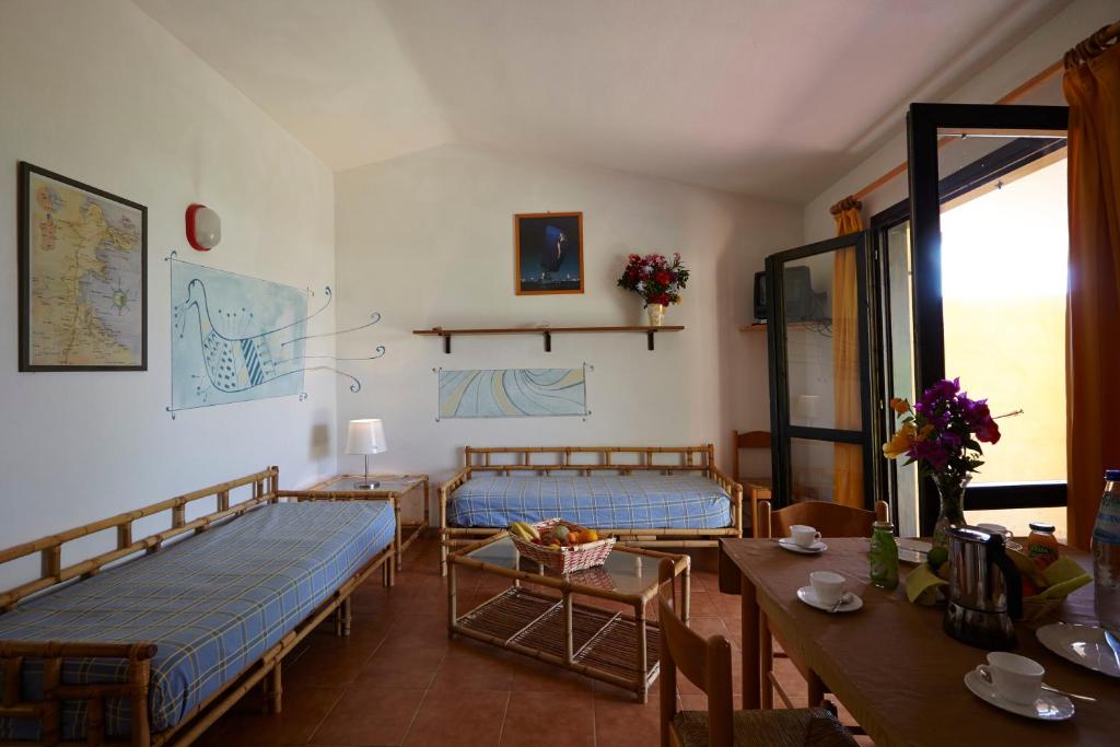 un salon avec deux lits et une table dans l'établissement Residence Baia Salinedda, à San Teodoro 32 autres photos