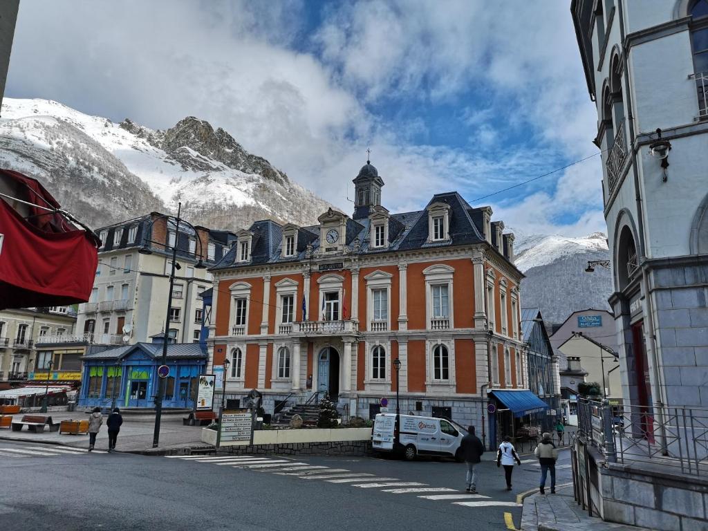 un grand bâtiment orange en face d'une montagne dans l'établissement Valériane, à Cauterets
