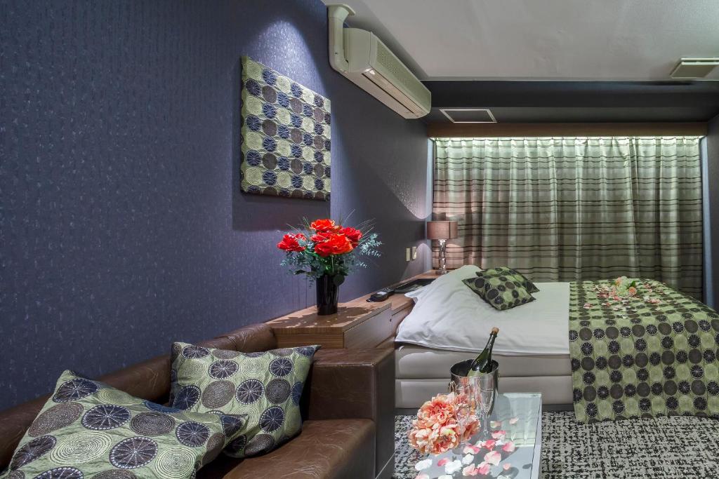 une chambre avec un lit, un canapé et une table dans l'établissement Restay Hiroshima (Adult Only), à Hiroshima