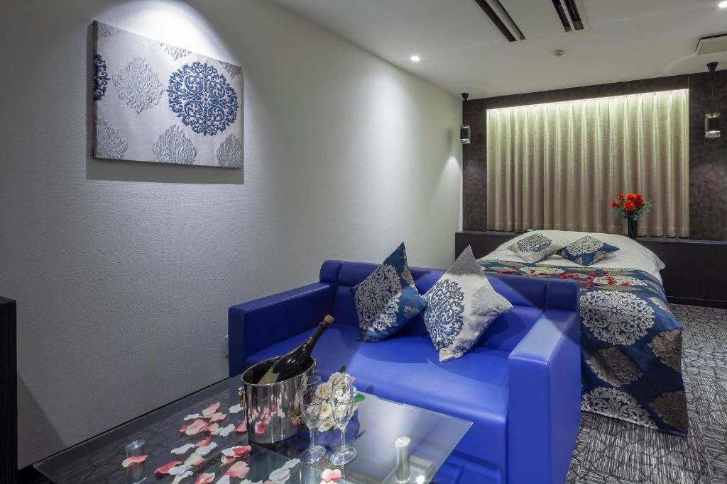 - un salon avec un canapé bleu et un lit dans l'établissement Restay Hiroshima (Adult Only), à Hiroshima