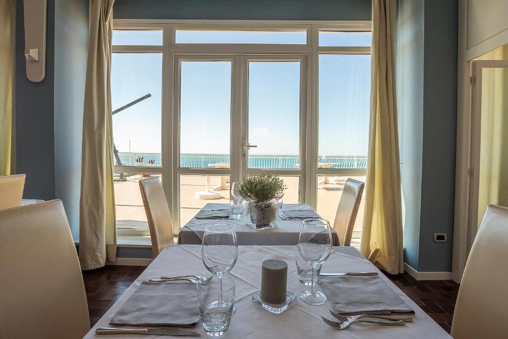 - une table avec des verres à vin et une vue sur l'océan dans l'établissement Hotel Rex, à Livourne