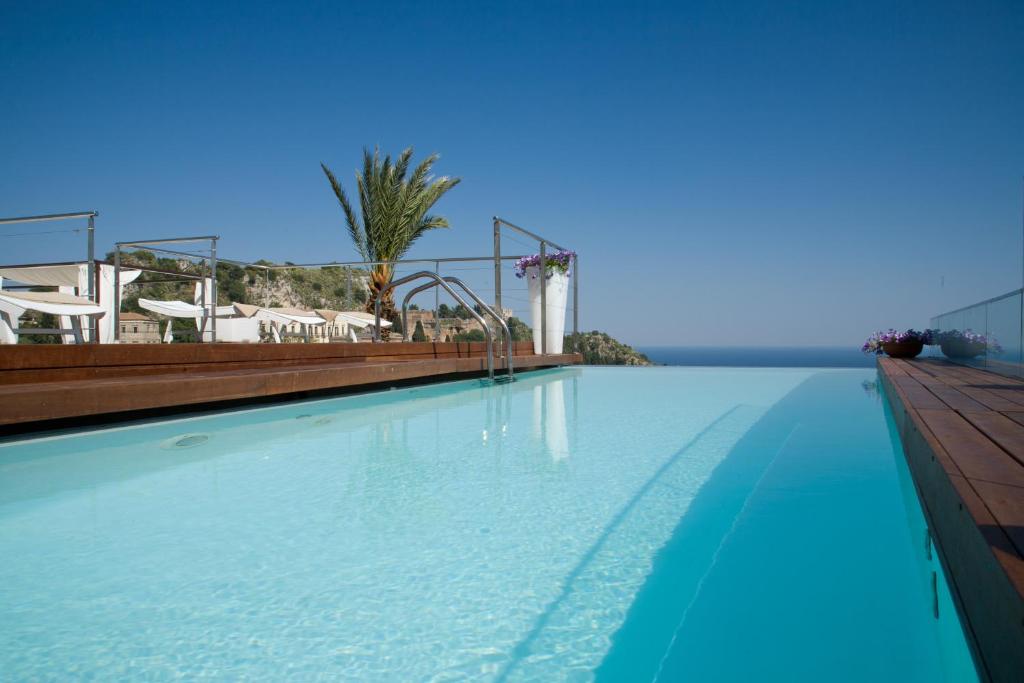 une piscine à l'eau bleue dans un complexe hôtelier dans l'établissement Il Piccolo Giardino GH ***Superior, à Taormine