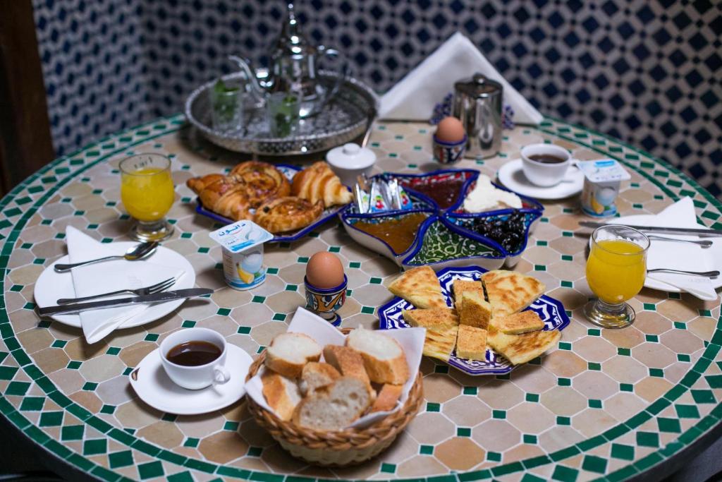une table avec un petit-déjeuner composé de pain et de jus d'orange dans l'établissement Dar Meknes Tresor, à Meknès