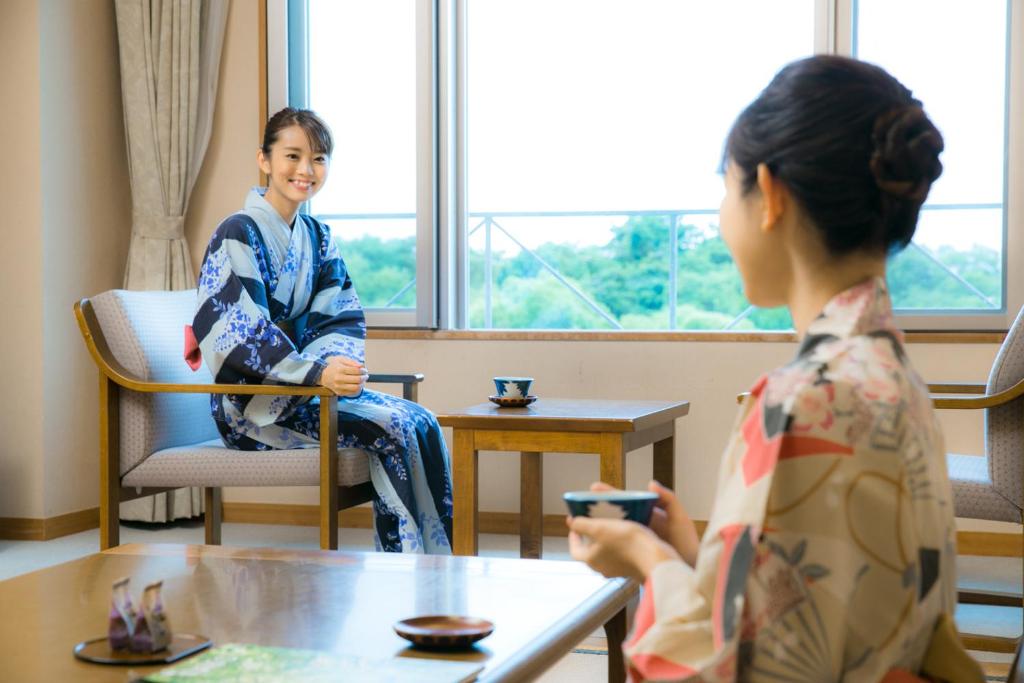 une femme assise dans une pièce avec une femme jouant à un jeu vidéo dans l'établissement Kyukamura Ura-Bandai, à Kitashiobara