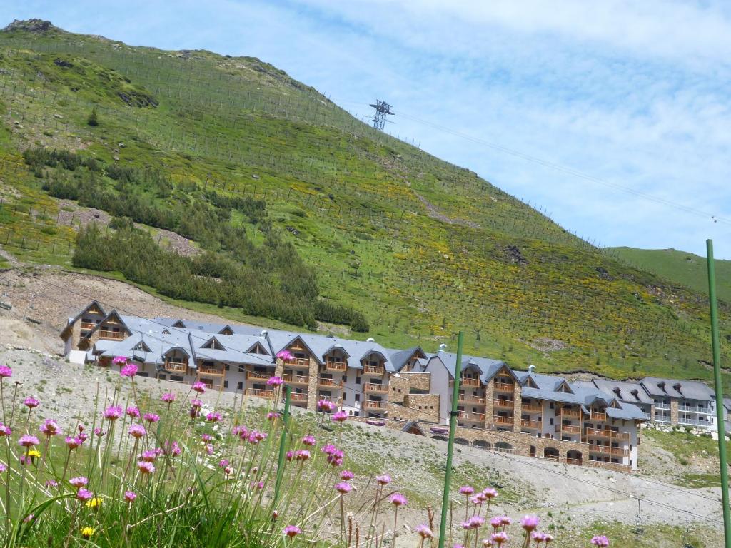 un groupe de bâtiments sur une colline avec des fleurs dans l'établissement Résidence Mer & Golf Tourmalet, à La Mongie