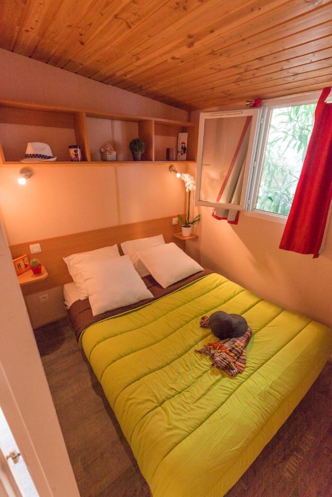 une chambre avec un lit vert avec un chien allongé dessus dans l'établissement Camping Cap Sud, à Alénya