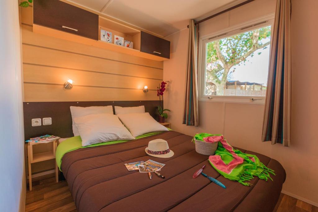 Cette petite chambre comprend un lit avec un chapeau et une fenêtre. dans l'établissement Camping Cap Sud, à Alénya