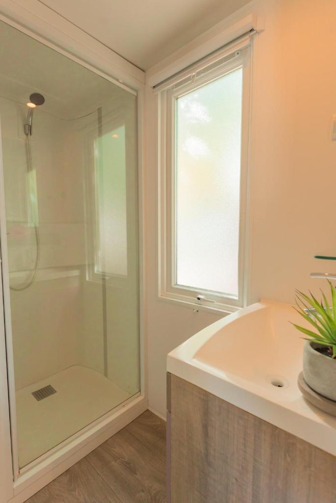 La salle de bains est pourvue d'une douche, d'une baignoire et d'une fenêtre. dans l'établissement Camping Cap Sud, à Alénya 52 autres photos