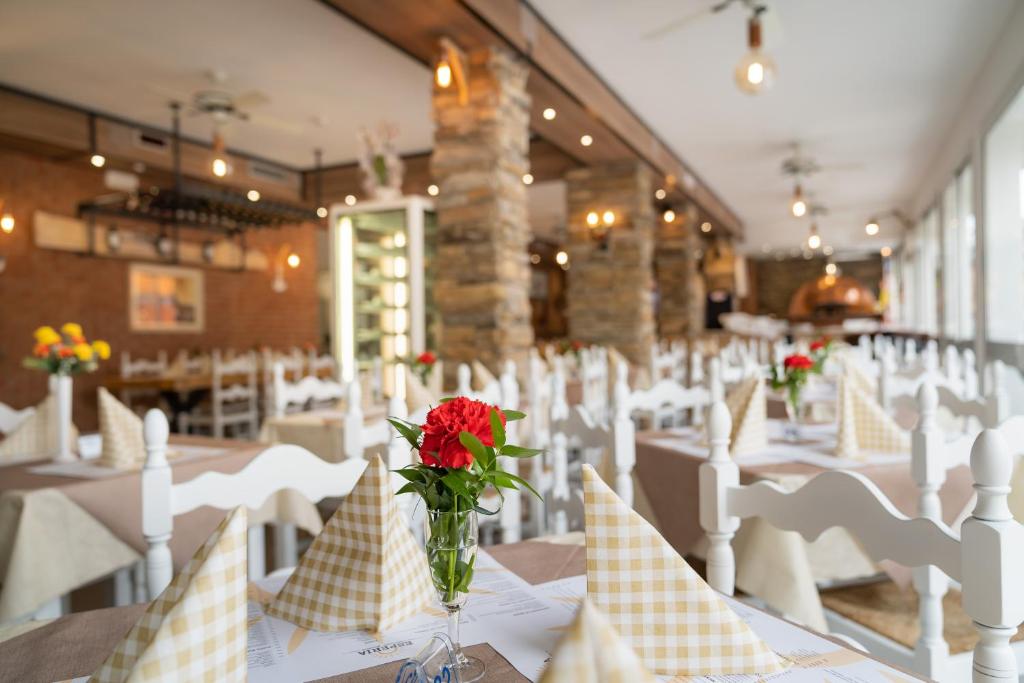 une salle à manger avec des chaises blanches et un vase de fleurs dans l'établissement Hotel Esperia, à Caorle
