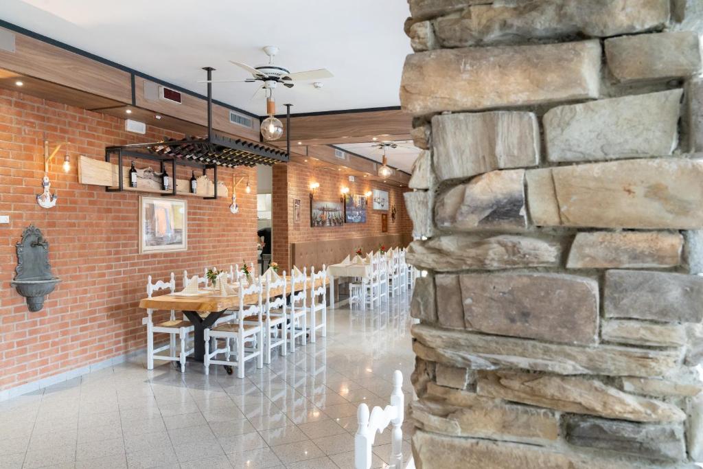 une salle à manger avec un mur en pierre, une table et des chaises dans l'établissement Hotel Esperia, à Caorle