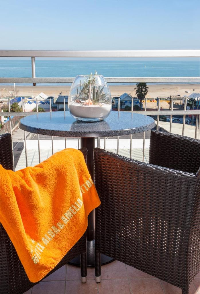 - une table avec des chaises et un bol en verre sur la plage dans l'établissement Baby Family Hotel Alda Amelia, à Cattolica
