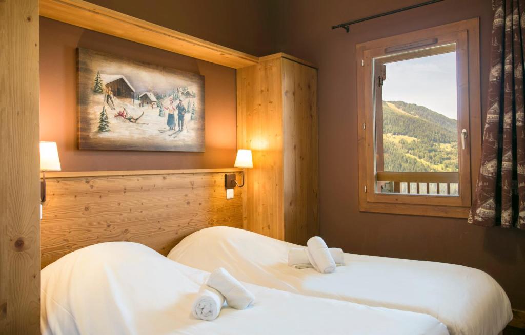 deux lits dans une chambre d'hôtel avec une fenêtre dans l'établissement Résidence Club mmv L'Étoile des Cimes ****, à Sainte-Foy-Tarentaise