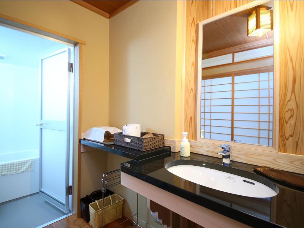une salle de bain avec un lavabo et un miroir dans l'établissement Kamei no Yu, à Yamanouchi