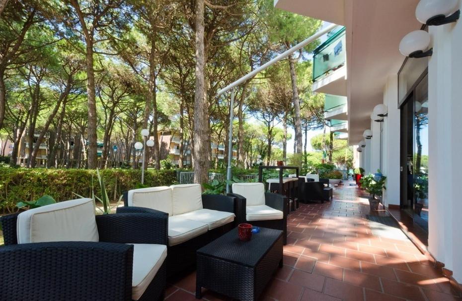 un patio avec des chaises et des tables blanches et des arbres dans l'établissement Hotel King, à Lido di Jesolo