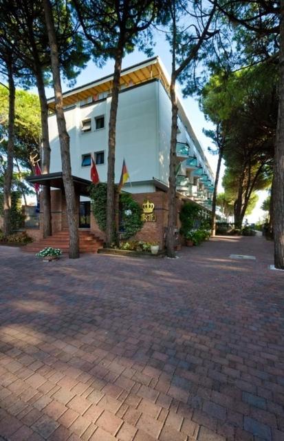 un grand bâtiment avec des arbres devant dans l'établissement Hotel King, à Lido di Jesolo