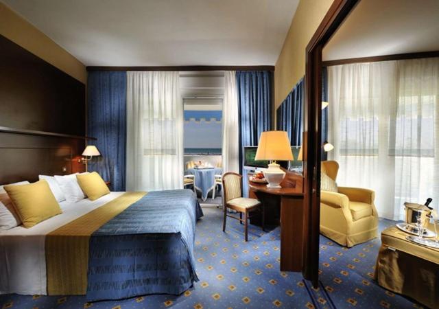 une chambre d'hôtel avec un lit, un bureau et une chaise dans l'établissement Hotel Corallo, à Bibione