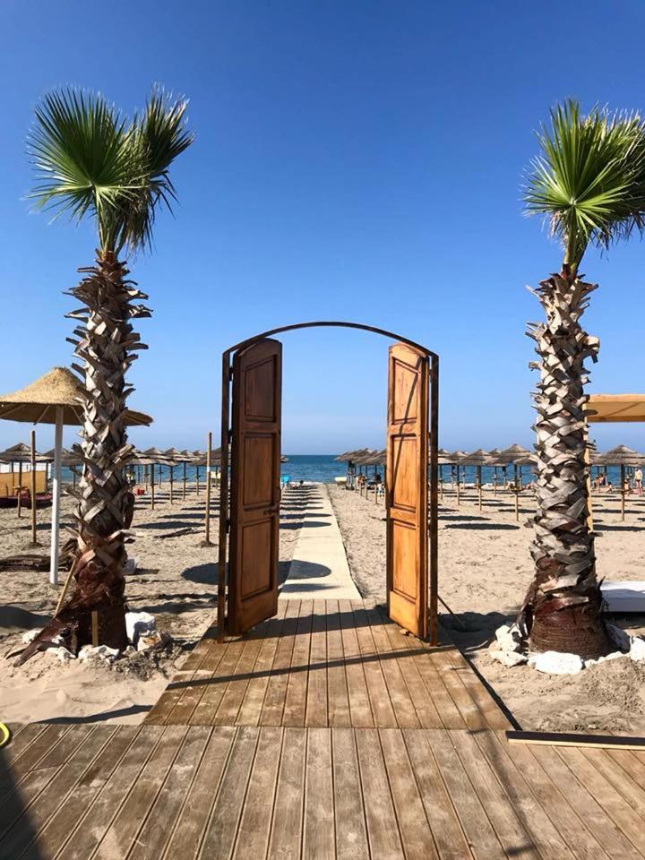 une porte ouverte sur une plage avec deux palmiers dans l'établissement Hotel La Terrazza, à Barletta