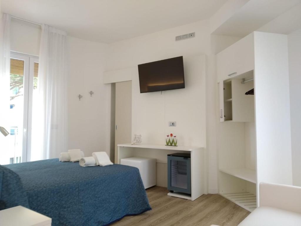 - une chambre blanche avec un lit bleu et une télévision dans l'établissement Hotel Residence Mara, à Lido di Jesolo