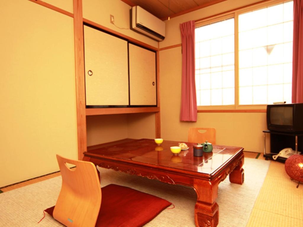 un salon avec une table et des chaises en bois dans l'établissement Hatoguruma Kawabata, à Nozawa Onsen