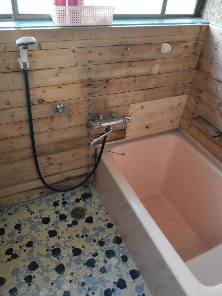 une baignoire avec un tuyau fixé à un mur en bois dans l'établissement Izu Hokkawa Seaside Guesthouse 伊豆北川の家, à Higashiizu 37 autres photos
