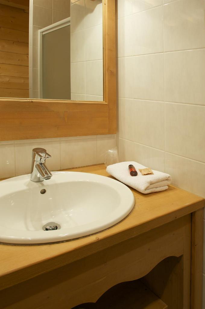 une salle de bain avec un lavabo blanc et un miroir dans l'établissement Hôtel L'Accroche Coeur, à La Rosière 27 autres photos